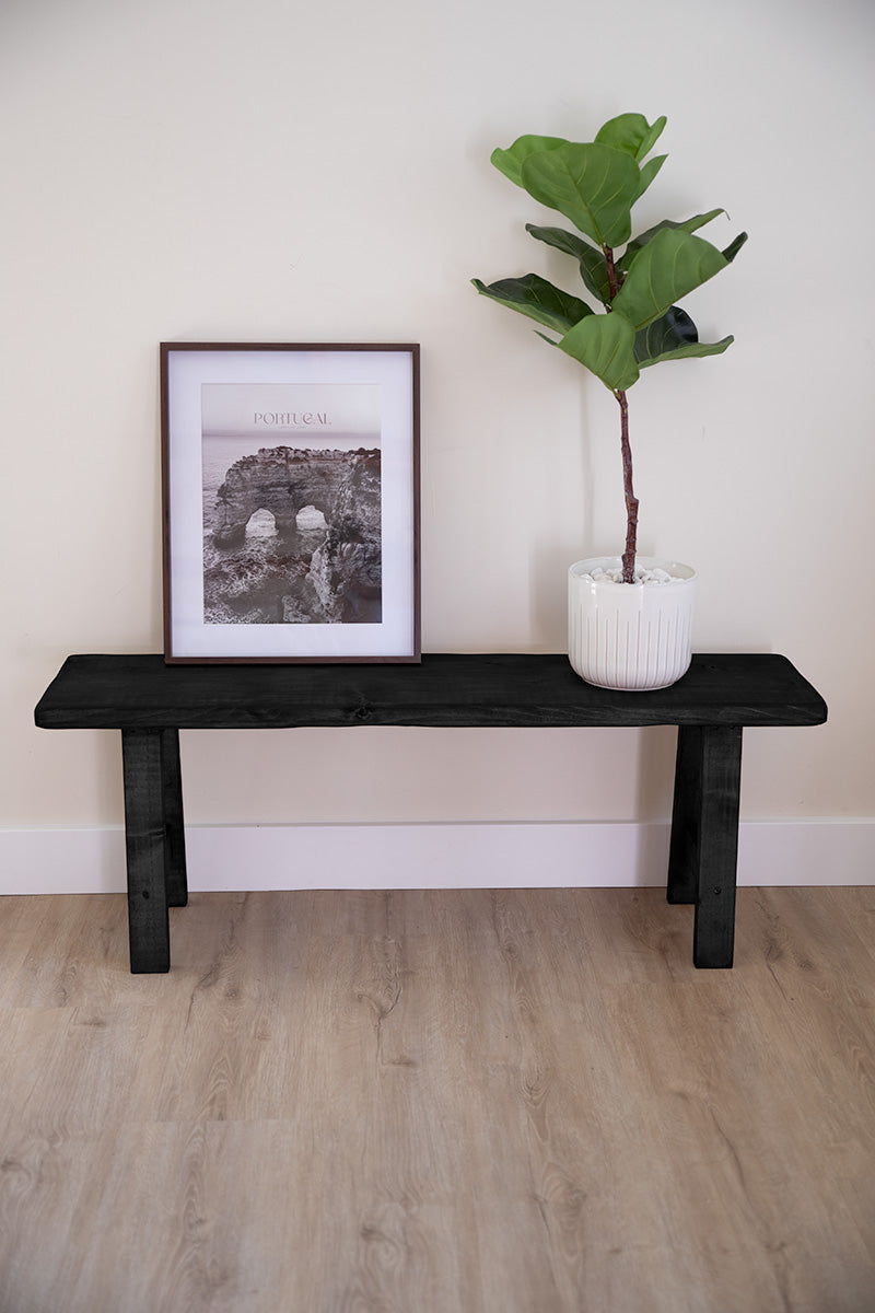 Zwart houten bankje dat dienstdoet als zitbank aan het voeteneind van het bed of voor woonaccessoires