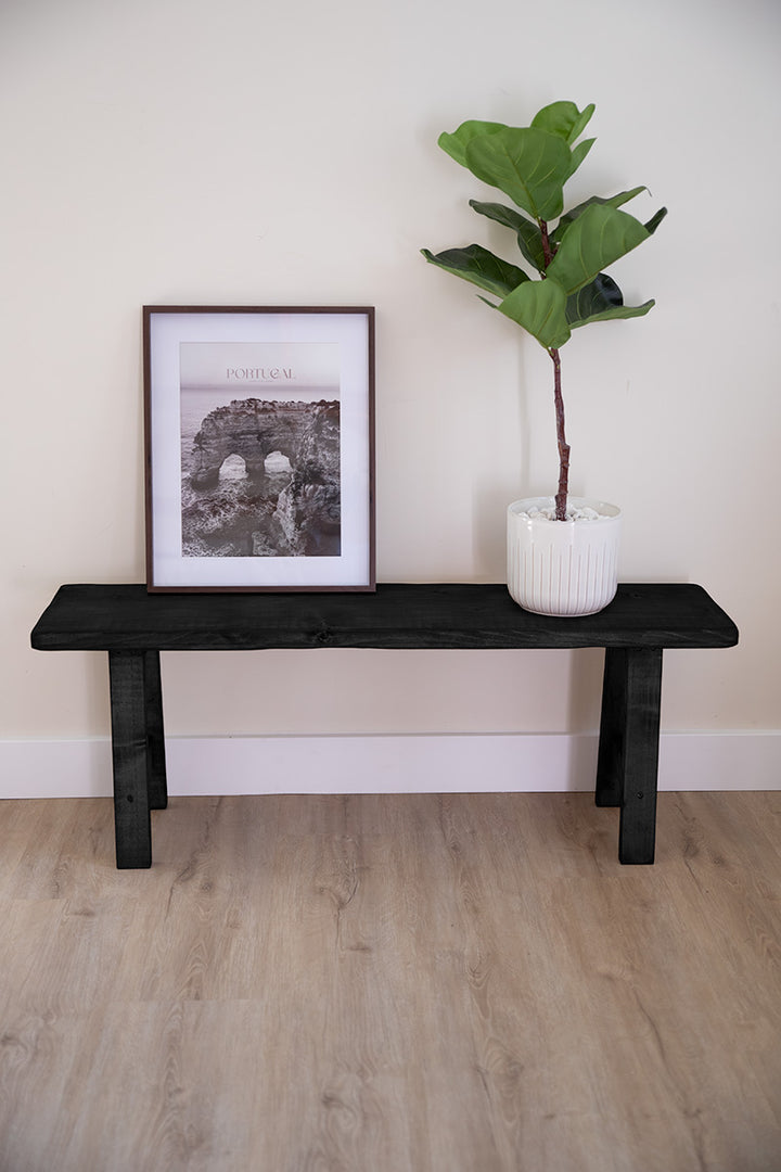 Zwart houten bankje dat dienstdoet als zitbank aan het voeteneind van het bed of voor woonaccessoires