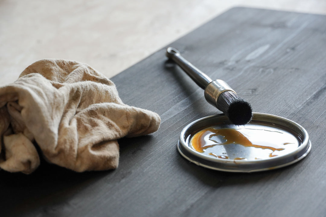 Beits en een kwast van Baan Woods liggend op een houten zwarte plank