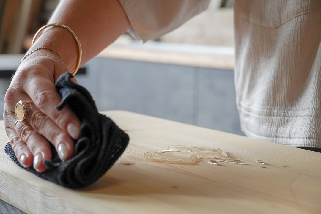 Waterdruppels op waterafstotend meubel van Baan Woods worden afgenomen met een doek