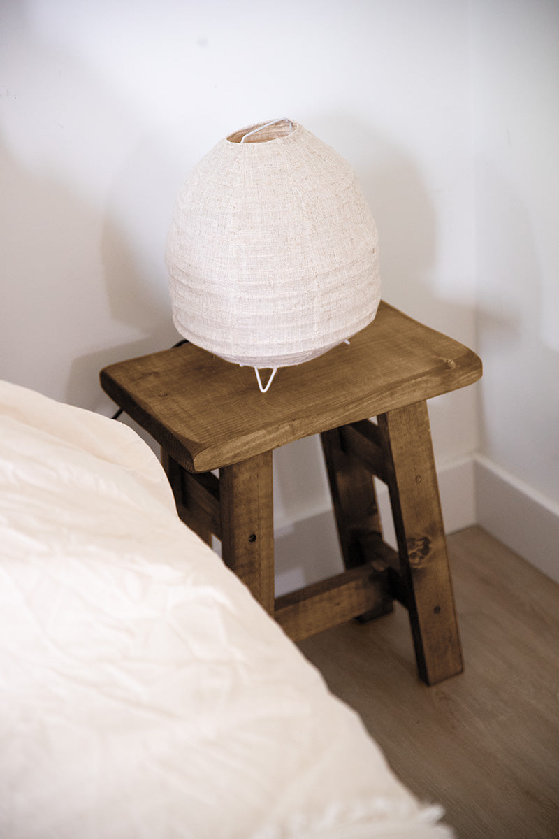 Multifunctionele houten kruk die ook gebruikt kan worden als nachtkastje naast een bed 