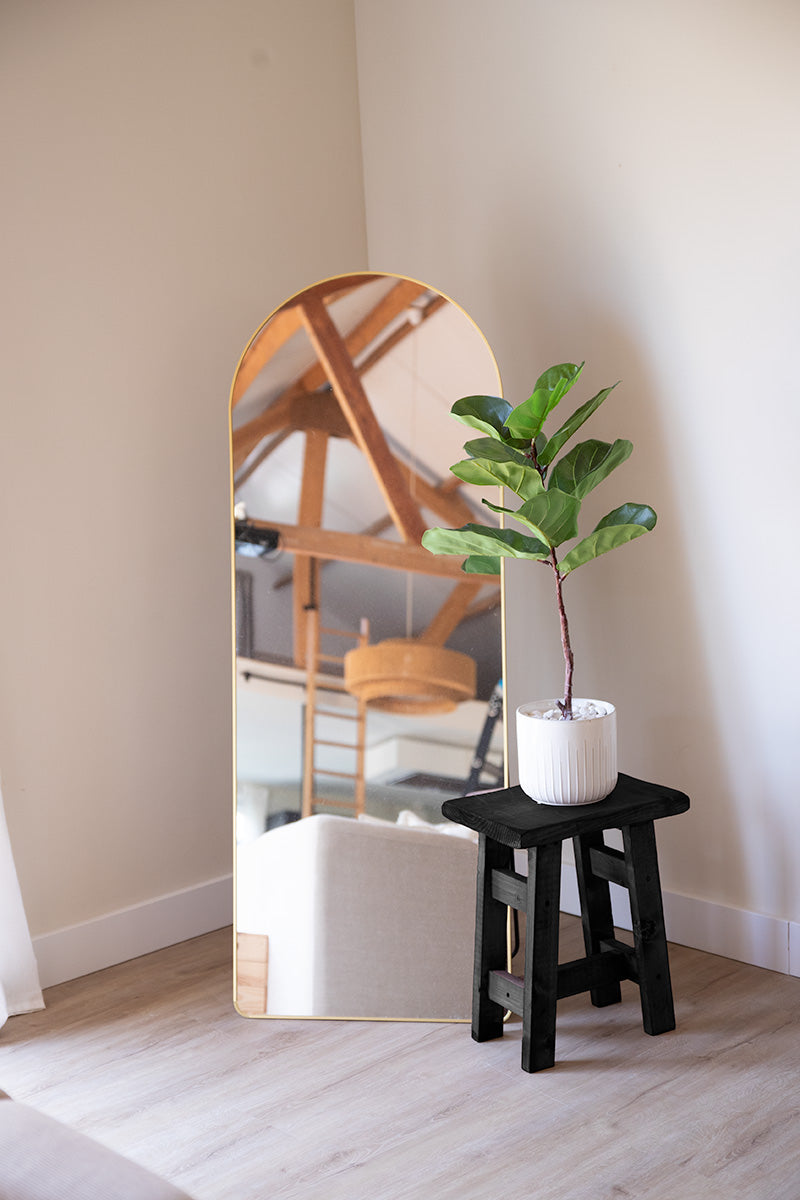 Zwarte kruk van hout met plant erop in woonkamerhoek