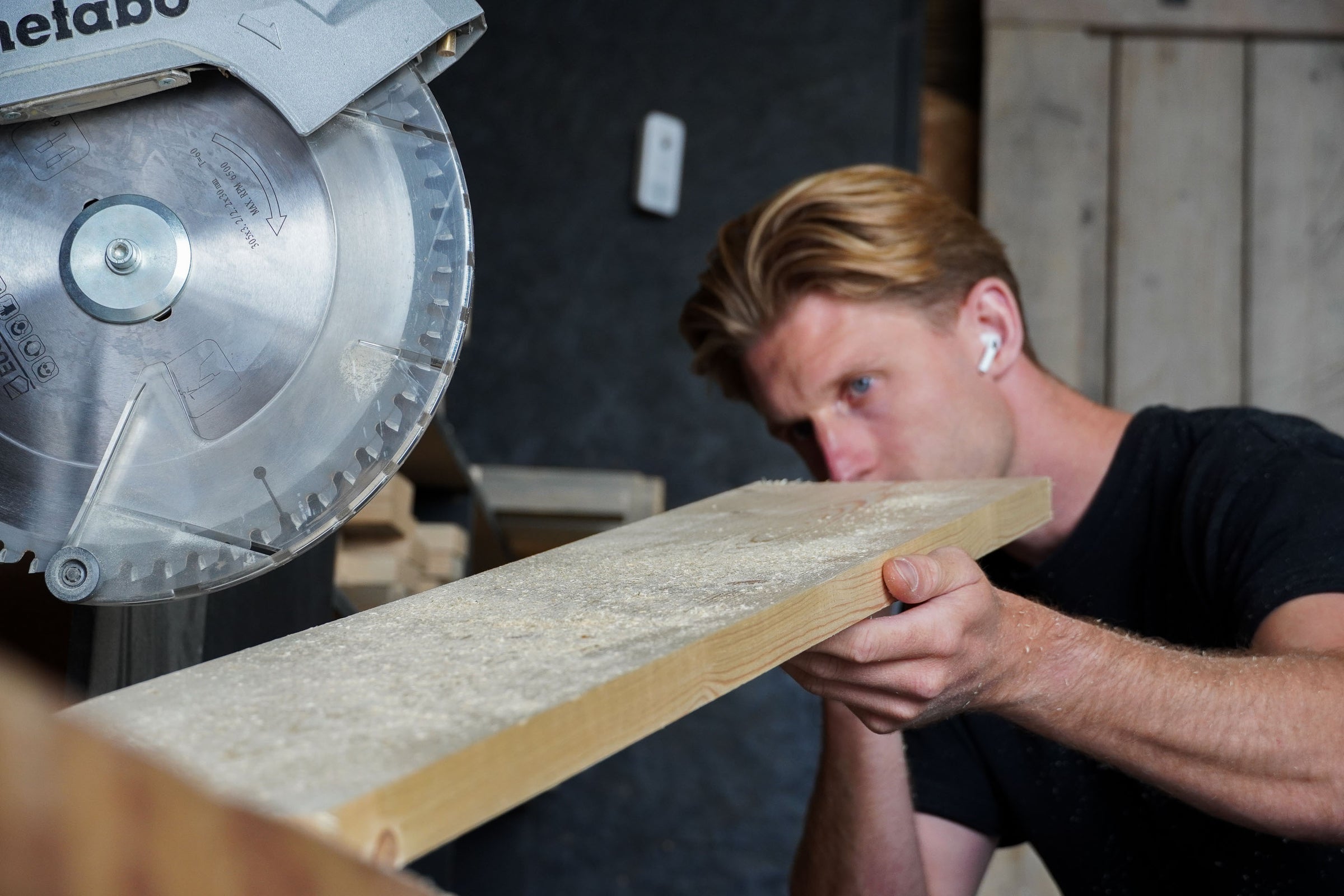 Timmerman beoordeelt houten plank in werkplaats van Baan Woods