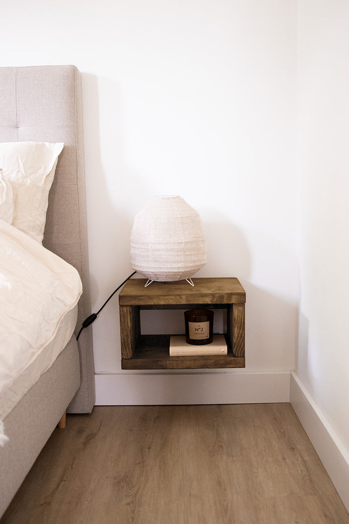 Zwevend nachtkastje van hout is opgehangen aan de muur van de slaapkamer