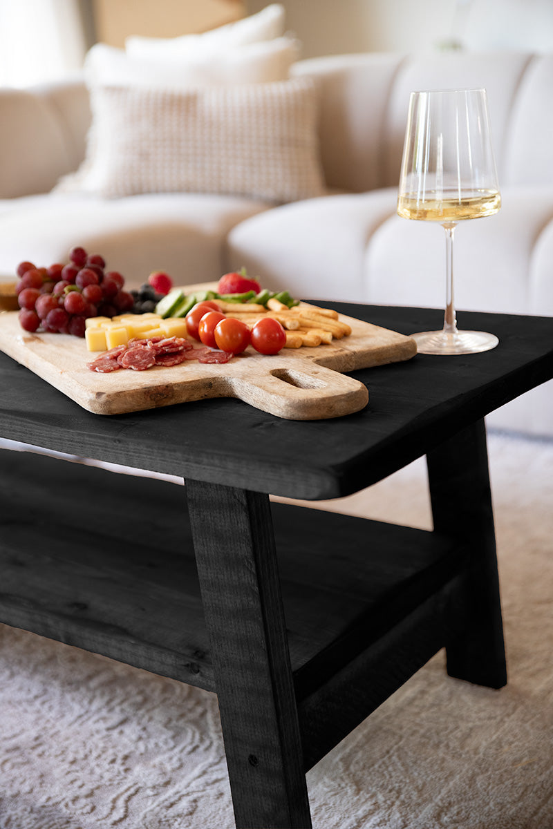 Robuuste zwarte houten salontafel van Baan Woods met een borrelplank en een wijntje 