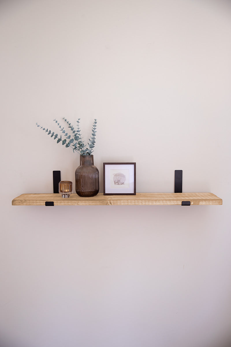 Houten wandplank in de kleur lichtbruin bevestigd met zwarte stalen beugels aan de muur