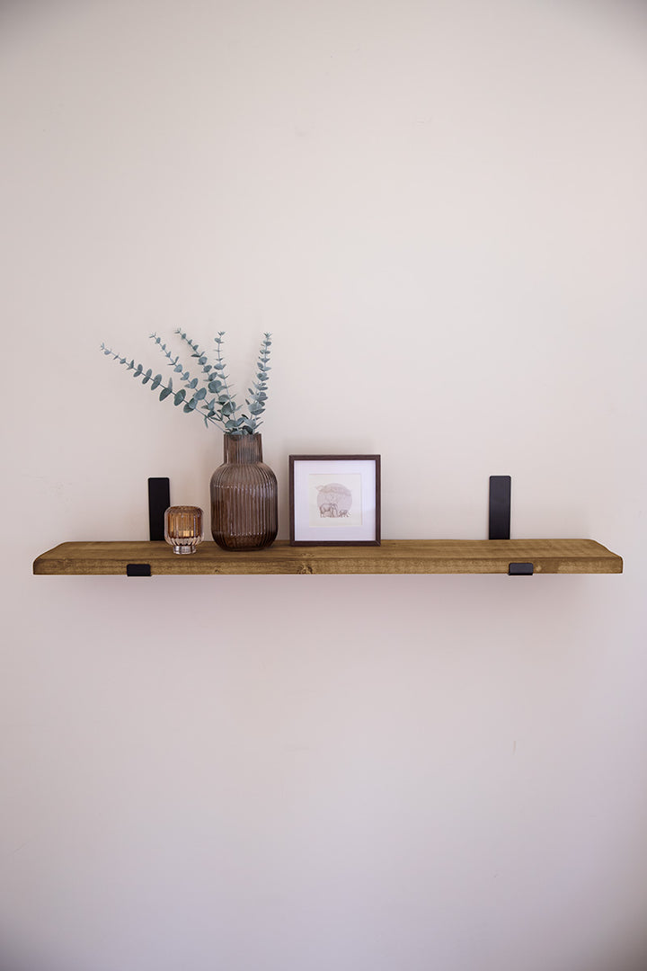 Houten wandplank in de kleur middenbruin bevestigd met zwarte stalen beugels