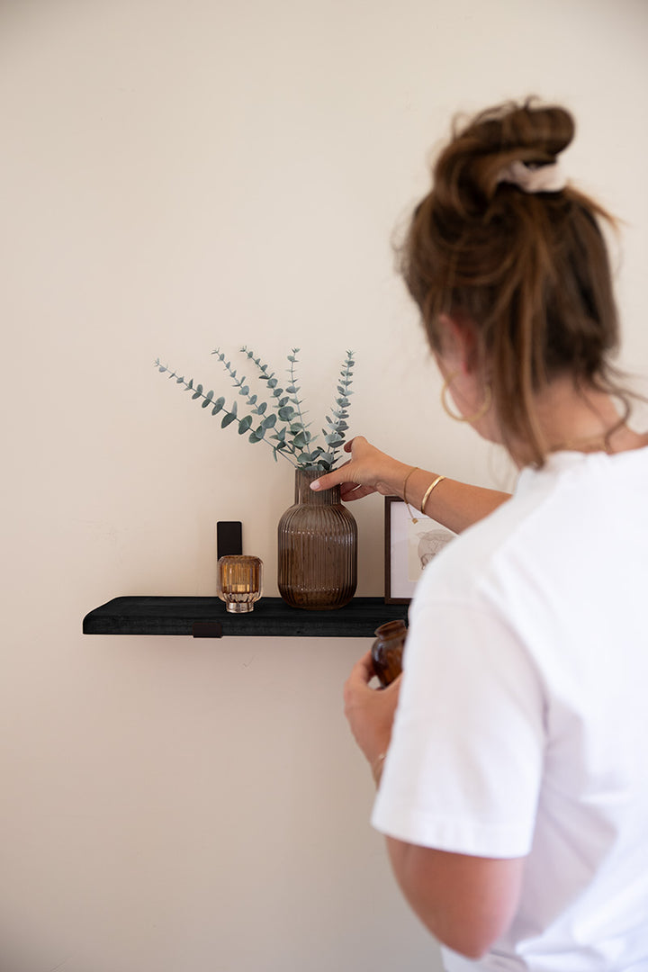 Zwarte wandplank van Baan Woods met beugels wordt gedecoreerd 