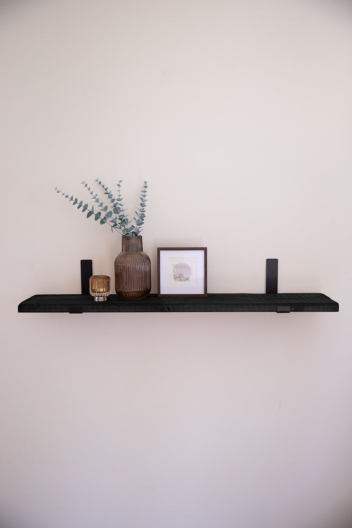 Houten wandplank in de kleur zwart bevestigd met zwarte stalen beugels