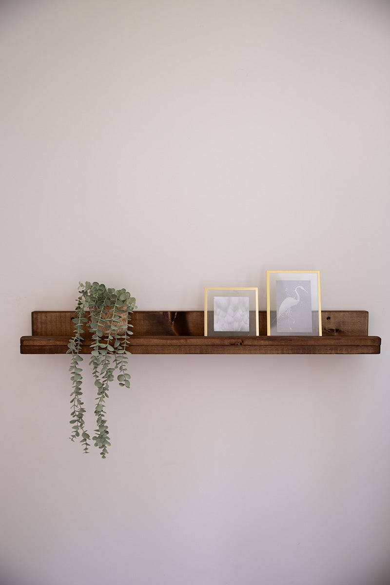 Donkerbruine wandplank van Baan Woods met een plantje en foto's