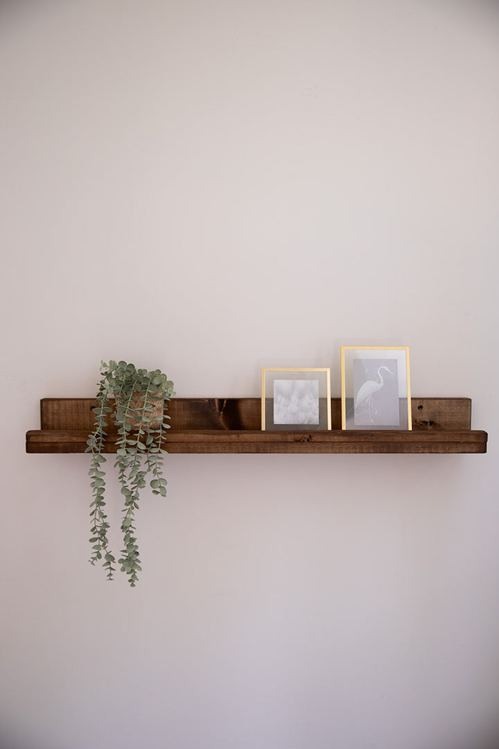 Donkerbruine wandplank van Baan Woods met een plantje en foto's